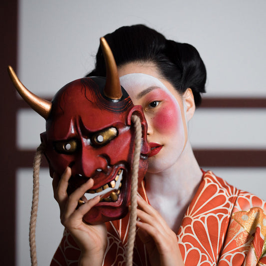 A japanese woman dressed in Kimono and holding a Oni Mask