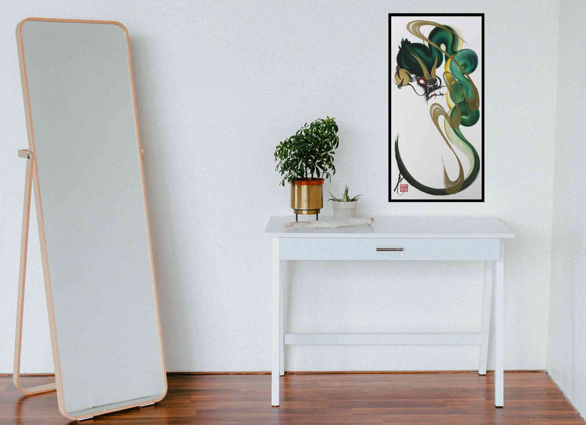A minimalist interior scene with a tall floor mirror on the left, a white console table with a small potted plant in the center, and a framed abstract green and black wall art print on the right against a white wall.